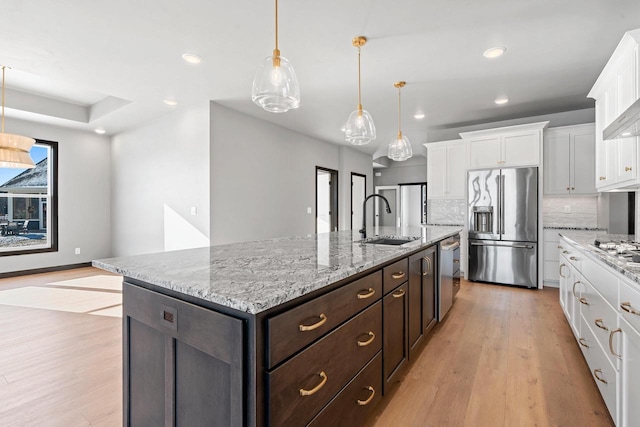 kitchen featuring stainless steel appliances, sink, white cabinets, backsplash, and hanging light fixtures