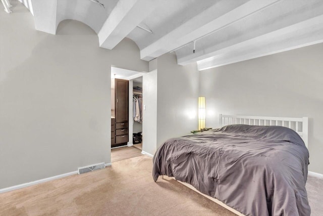 carpeted bedroom featuring a spacious closet, a closet, and beamed ceiling