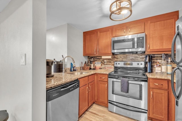 kitchen featuring light stone countertops, decorative backsplash, stainless steel appliances, and sink