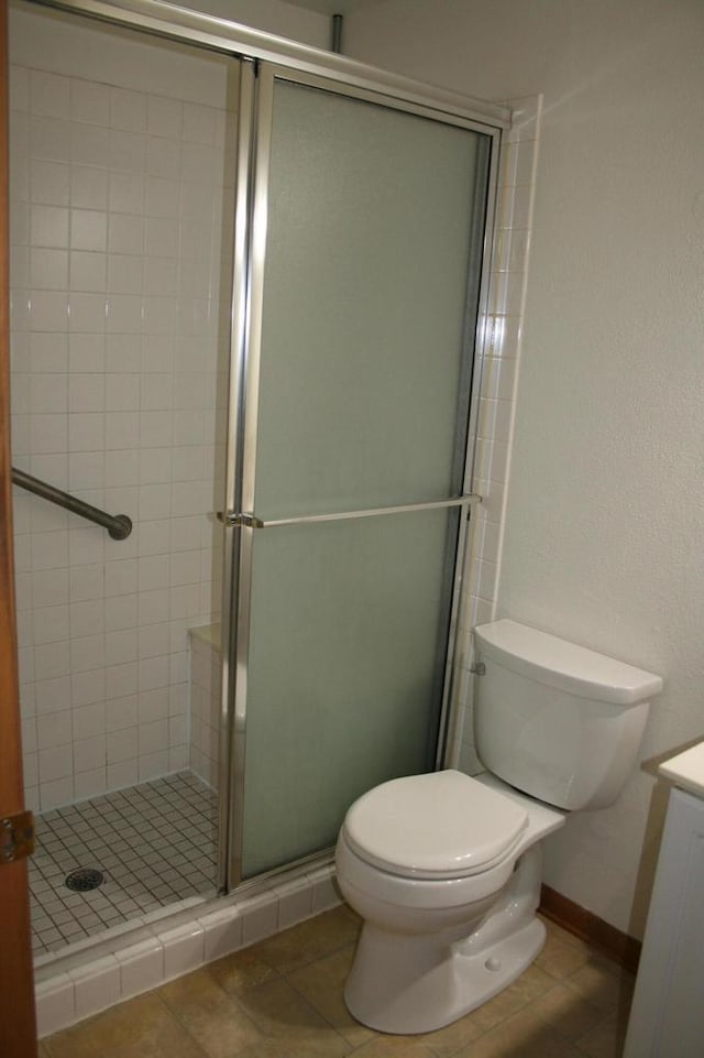 bathroom featuring tile patterned floors, vanity, toilet, and walk in shower