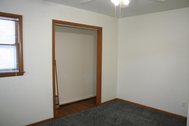 unfurnished bedroom featuring dark colored carpet, ceiling fan, and a closet