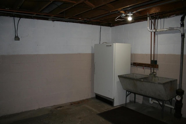 basement with white fridge and sink