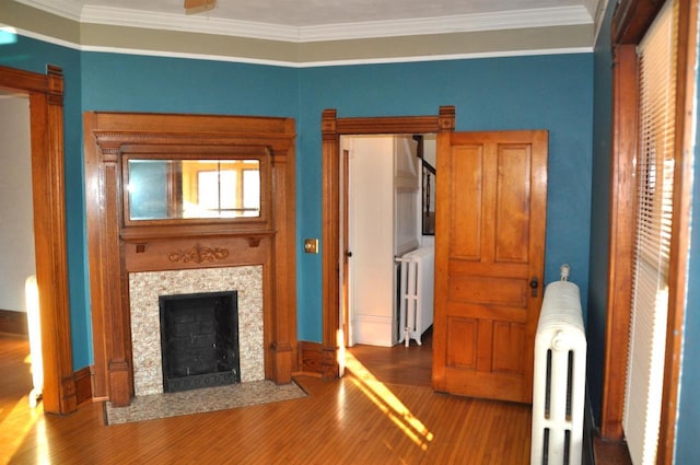 unfurnished living room with a tiled fireplace, crown molding, radiator heating unit, and hardwood / wood-style flooring