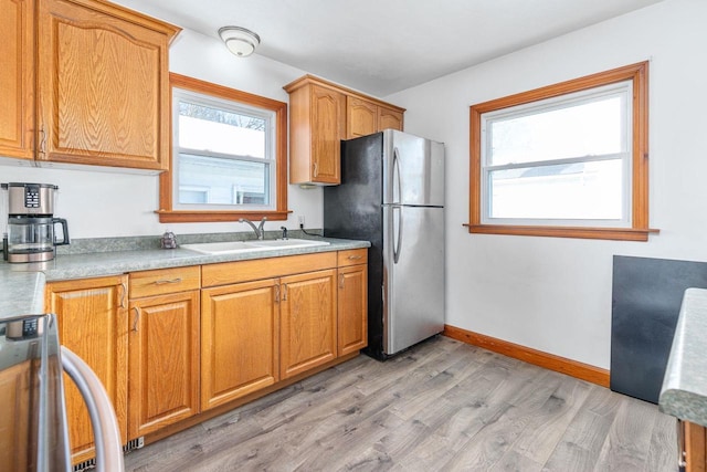 kitchen featuring stainless steel fridge, sink, light hardwood / wood-style floors, and range