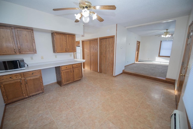 kitchen with built in desk, white fridge, baseboard heating, and ceiling fan