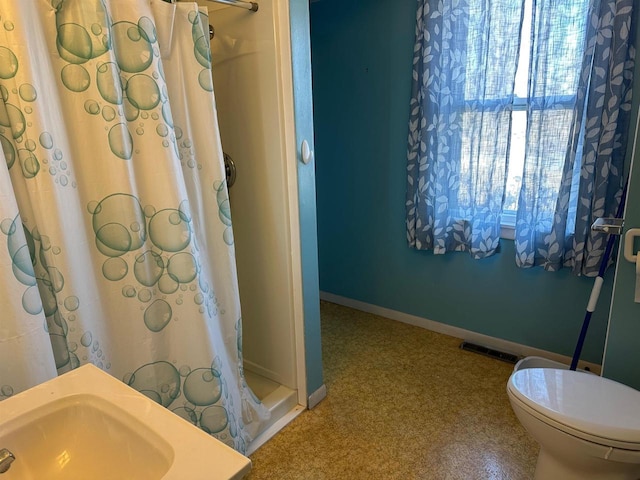 bathroom featuring toilet, walk in shower, and sink