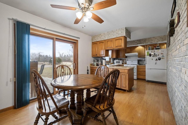 dining space with ceiling fan, brick wall, and light hardwood / wood-style flooring