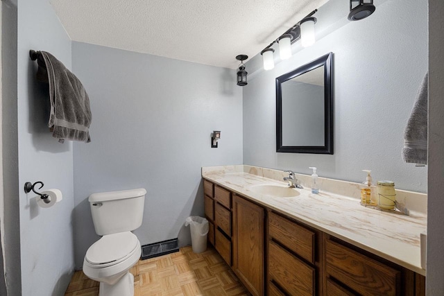 bathroom featuring vanity, toilet, parquet flooring, and a textured ceiling