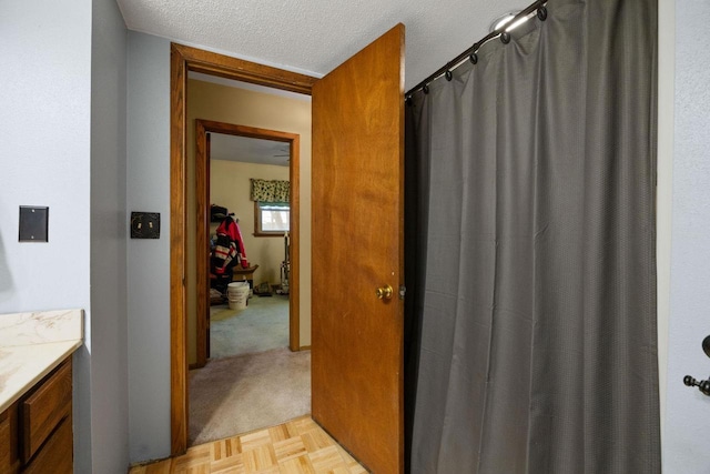 bathroom with vanity, parquet floors, and a textured ceiling