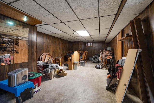 interior space featuring a drop ceiling and wooden walls