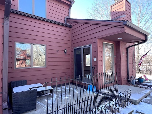 snow covered property entrance with a patio area