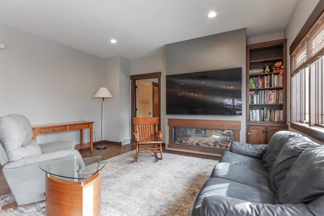 living room with built in shelves and hardwood / wood-style floors