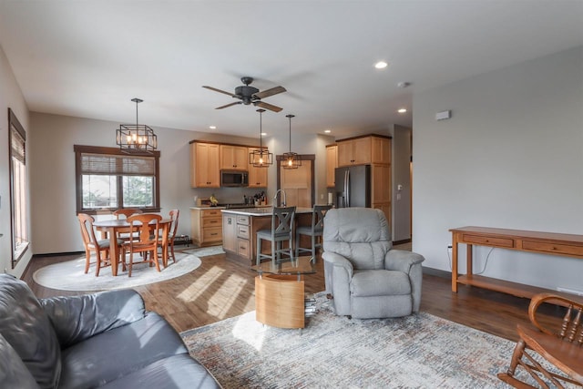 living room with ceiling fan with notable chandelier and light hardwood / wood-style flooring