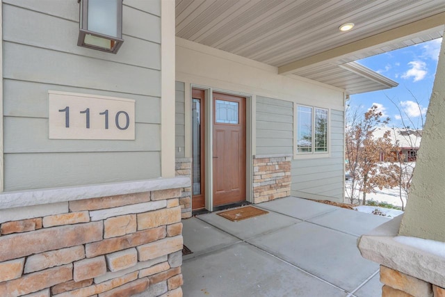 snow covered property entrance with covered porch