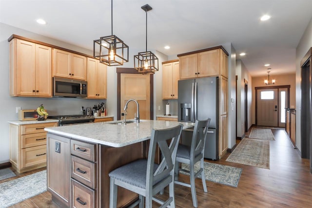 kitchen with sink, an island with sink, dark hardwood / wood-style floors, and appliances with stainless steel finishes