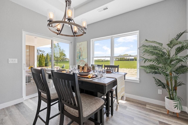 dining area with light wood finished floors, baseboards, visible vents, and a notable chandelier