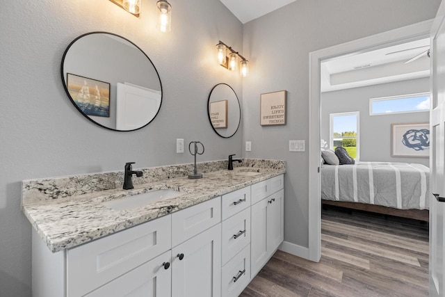 full bath with double vanity, ensuite bathroom, a sink, and wood finished floors