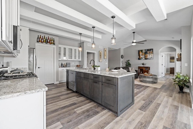 kitchen featuring arched walkways, a sink, white cabinetry, light wood-style floors, and appliances with stainless steel finishes