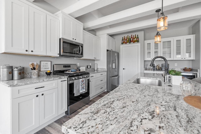 kitchen featuring stainless steel appliances, hanging light fixtures, glass insert cabinets, white cabinetry, and a sink