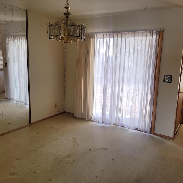 carpeted spare room featuring an inviting chandelier