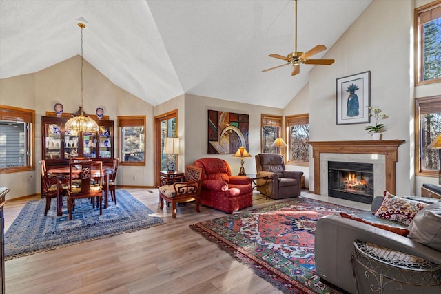 living room featuring ceiling fan, light wood-type flooring, a high end fireplace, and lofted ceiling