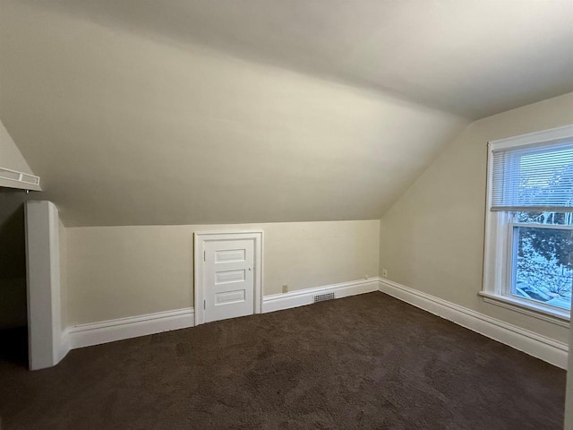 bonus room featuring dark carpet and vaulted ceiling