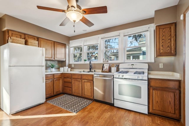 kitchen featuring ceiling fan, sink, white appliances, and light wood-type flooring