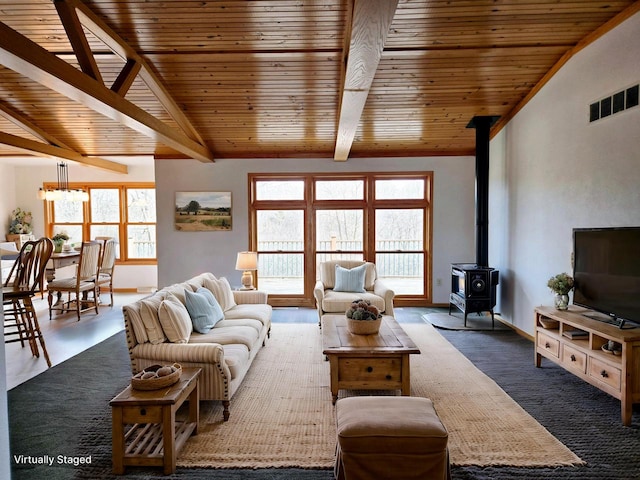 living room featuring a wood stove, lofted ceiling with beams, wooden ceiling, and a wealth of natural light