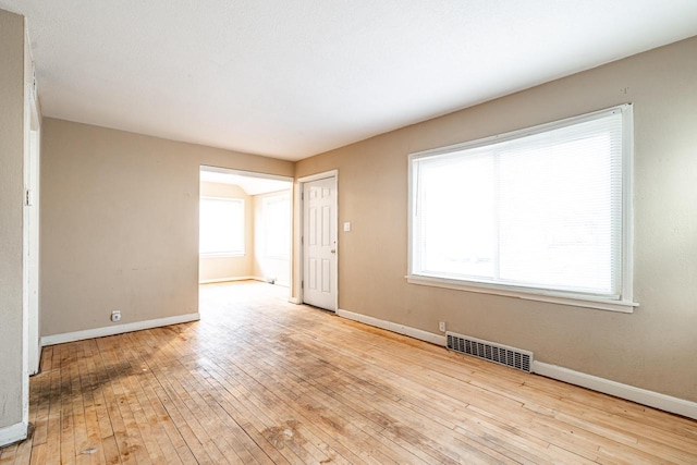 empty room with light hardwood / wood-style floors and plenty of natural light