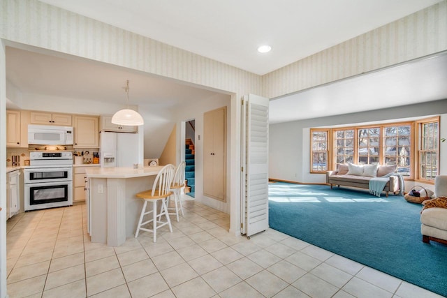 kitchen featuring pendant lighting, a center island, white appliances, light colored carpet, and a breakfast bar area