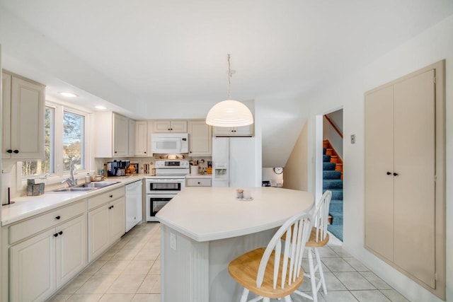 kitchen with white appliances, a kitchen breakfast bar, sink, hanging light fixtures, and a kitchen island