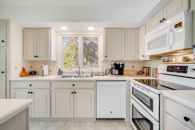 kitchen with decorative backsplash, light tile patterned floors, white appliances, and sink