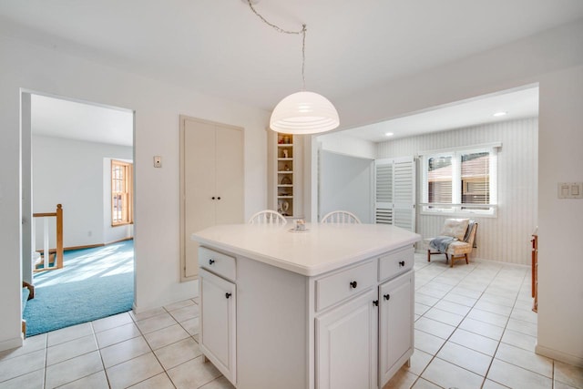 kitchen with pendant lighting, a kitchen island, white cabinets, and light colored carpet