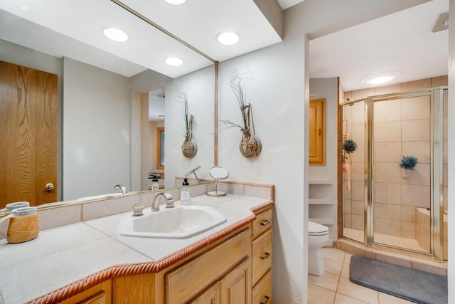 bathroom with tile patterned flooring, vanity, a shower with door, and toilet