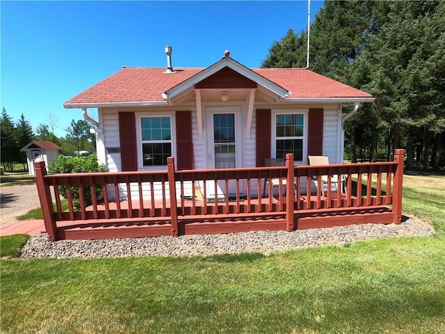 rear view of property featuring a yard and a storage unit