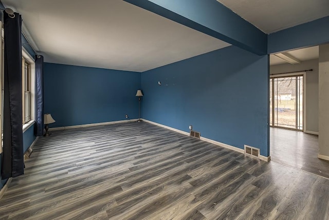 unfurnished room with beam ceiling and dark wood-type flooring