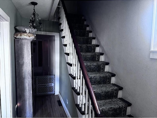 staircase with a chandelier and hardwood / wood-style floors