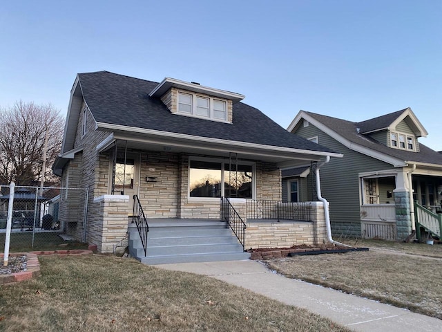 bungalow-style house with a front lawn and covered porch