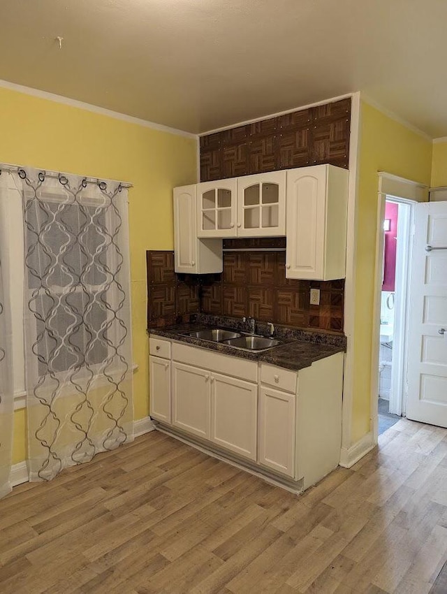 kitchen featuring white cabinets, decorative backsplash, sink, and light hardwood / wood-style flooring