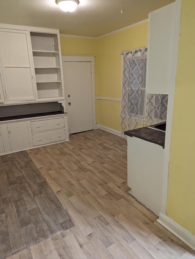 kitchen featuring white cabinets, ornamental molding, and light wood-type flooring