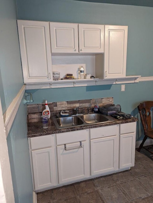 kitchen featuring white cabinetry, dark stone counters, and sink