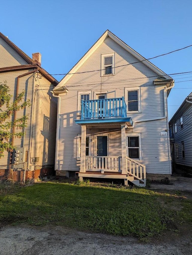 back of house featuring a balcony and a yard