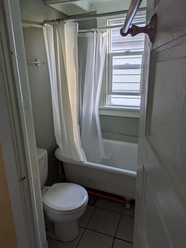 bathroom featuring tile patterned flooring, toilet, and shower / tub combo with curtain