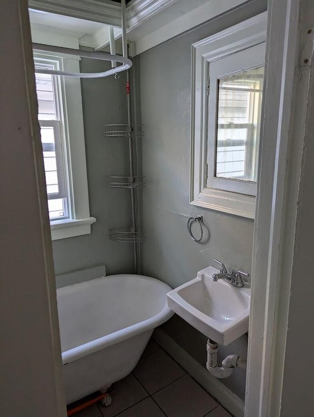 bathroom with tile patterned flooring, a bathtub, sink, and a wealth of natural light