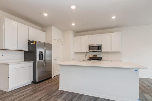 kitchen featuring white cabinets, wood-type flooring, stainless steel appliances, and an island with sink