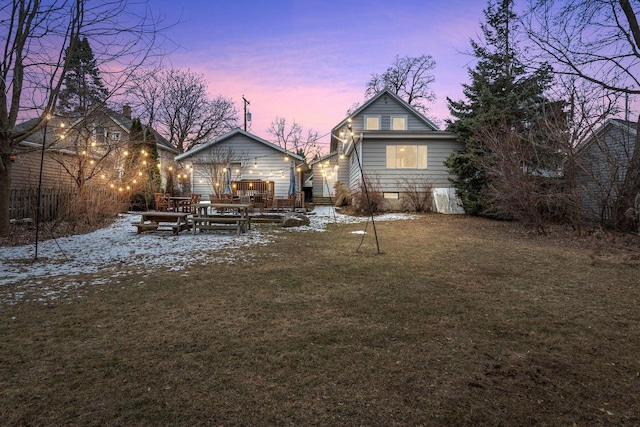 snow covered back of property featuring a lawn