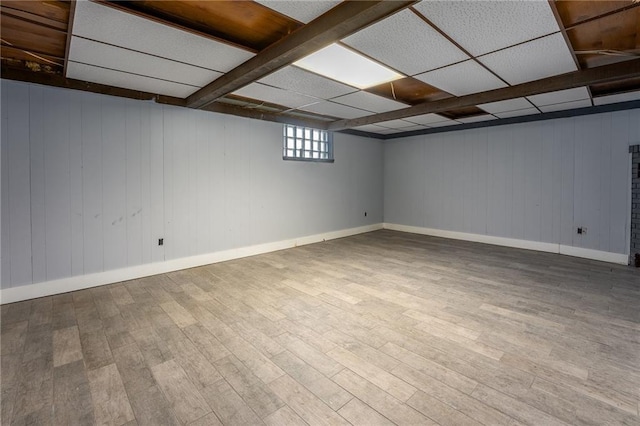 basement with a paneled ceiling and hardwood / wood-style flooring