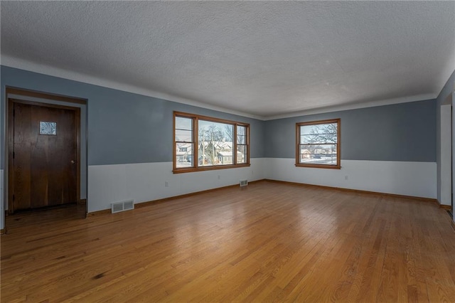 unfurnished room featuring a textured ceiling and light hardwood / wood-style flooring