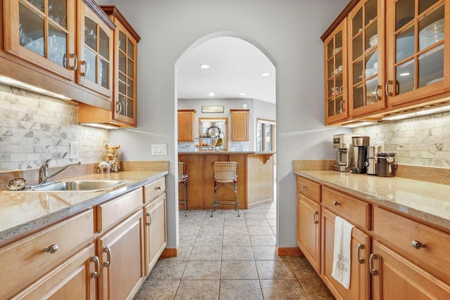 kitchen with sink, light tile patterned flooring, backsplash, and light stone countertops