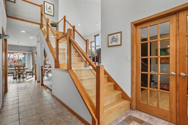 stairway with a notable chandelier and tile patterned floors